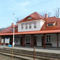 Budynek dworca kolejowego Wisła Uzdrowisko z czerwonym dachem i białymi ścianami.