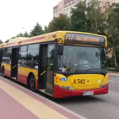 Żółty autobus miejski z czerwonymi elementami, z wyświetlaczem "717 DW ZACHODNI", stoi na przystanku.